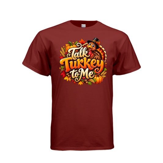 Talk Turkey to Me funny Thanksgiving T-shirt with smiling turkey wearing a pilgrim hat, pumpkins, autumn leaves, and festive lettering.